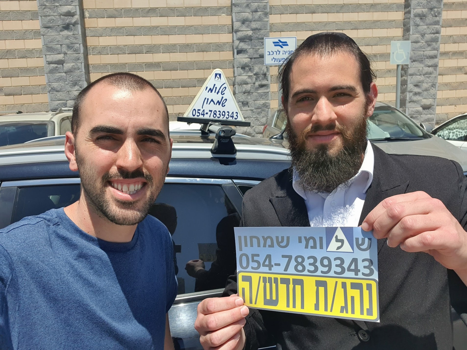 תלמיד עם שלומי שמחון, מורה נהיגה, מחזיק שלט "נהג חדש" לאחר המבחן – תמונה 59