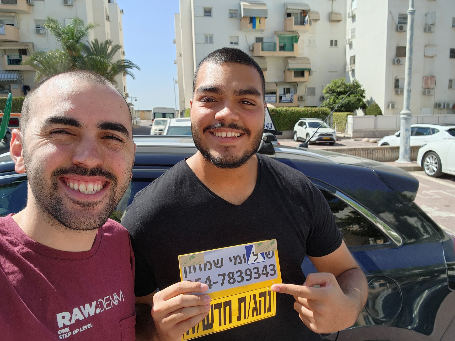 תלמיד עם שלומי שמחון, מורה נהיגה, מחזיק שלט "נהג חדש" לאחר המבחן – תמונה 20