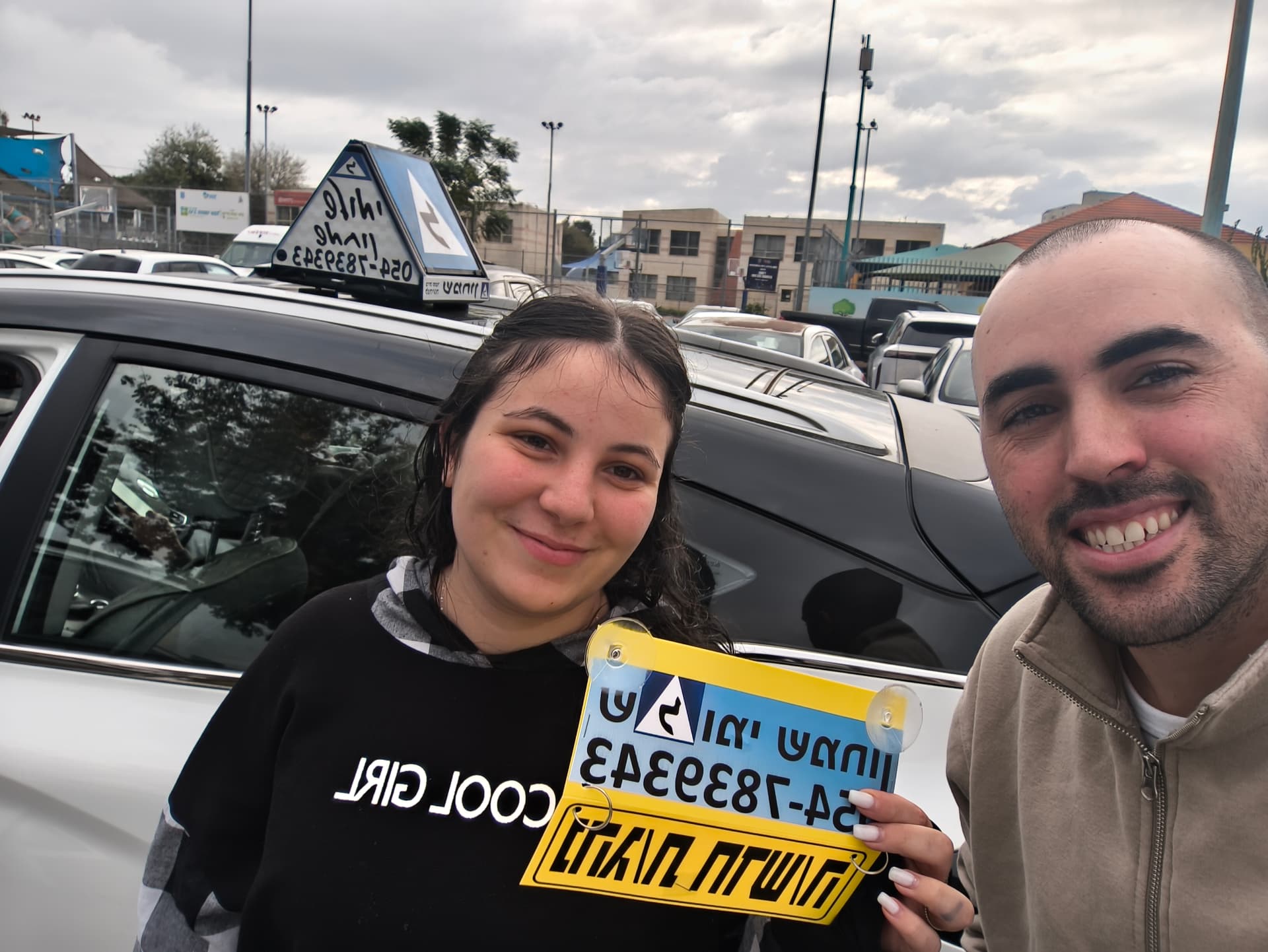 תלמיד עם שלומי שמחון, מורה נהיגה, מחזיק שלט "נהג חדש" לאחר המבחן – תמונה 28