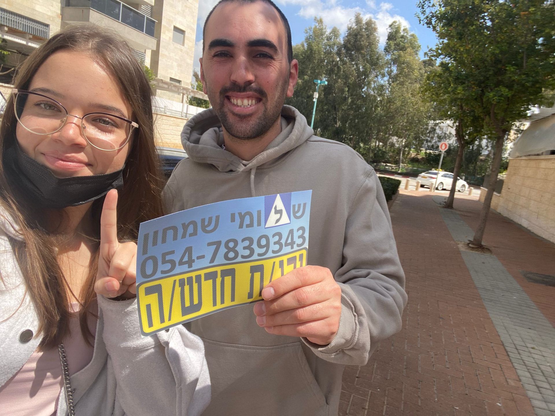 תלמיד עם שלומי שמחון, מורה נהיגה, מחזיק שלט "נהג חדש" לאחר המבחן – תמונה 47