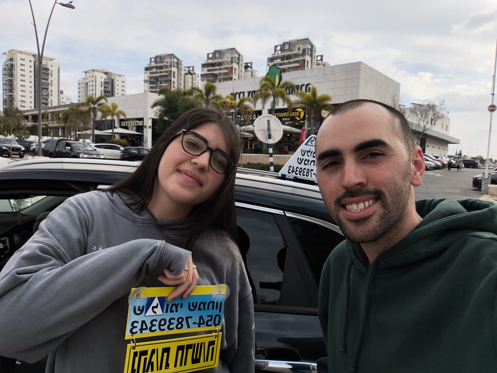 תלמיד עם שלומי שמחון, מורה נהיגה, מחזיק שלט "נהג חדש" לאחר המבחן – תמונה 45