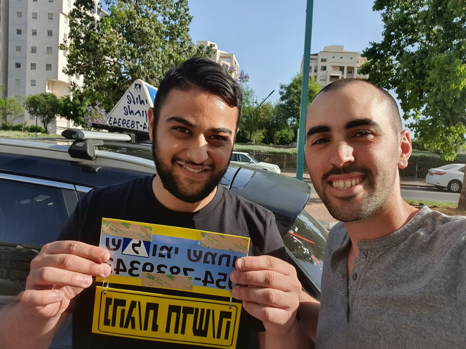תלמיד עם שלומי שמחון, מורה נהיגה, מחזיק שלט "נהג חדש" לאחר המבחן – תמונה 39