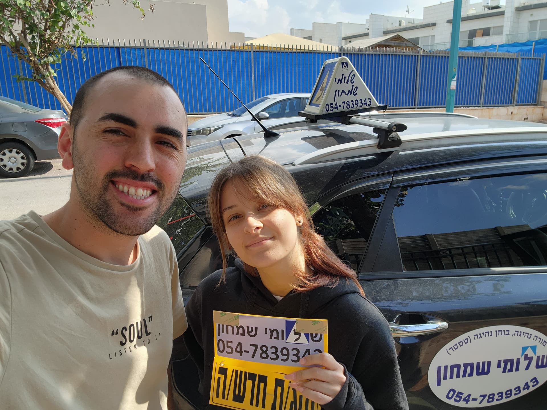 תלמיד עם שלומי שמחון, מורה נהיגה, מחזיק שלט "נהג חדש" לאחר המבחן – תמונה 22