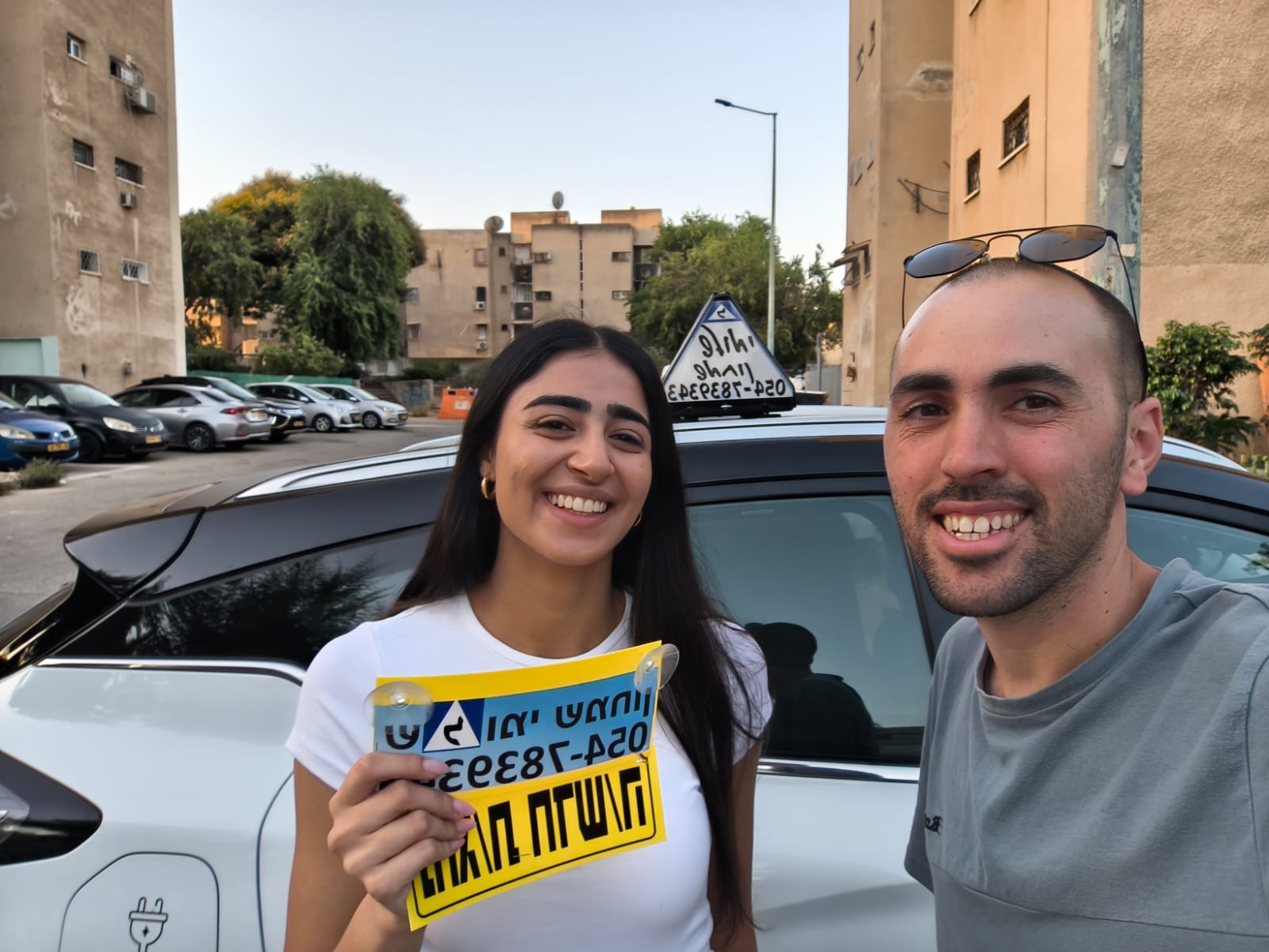 תלמיד עם שלומי שמחון, מורה נהיגה, מחזיק שלט "נהג חדש" לאחר המבחן – תמונה 36