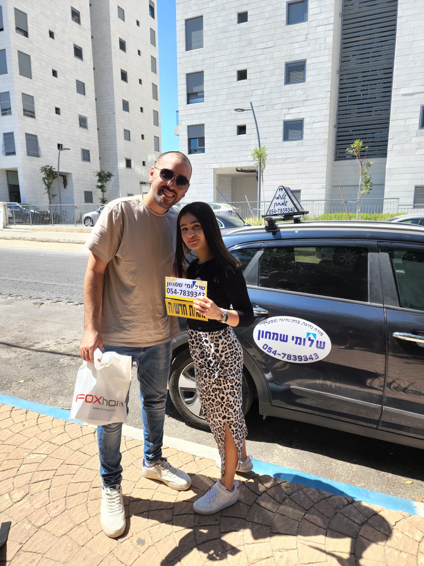 תלמיד עם שלומי שמחון, מורה נהיגה, מחזיק שלט "נהג חדש" לאחר המבחן – תמונה 5