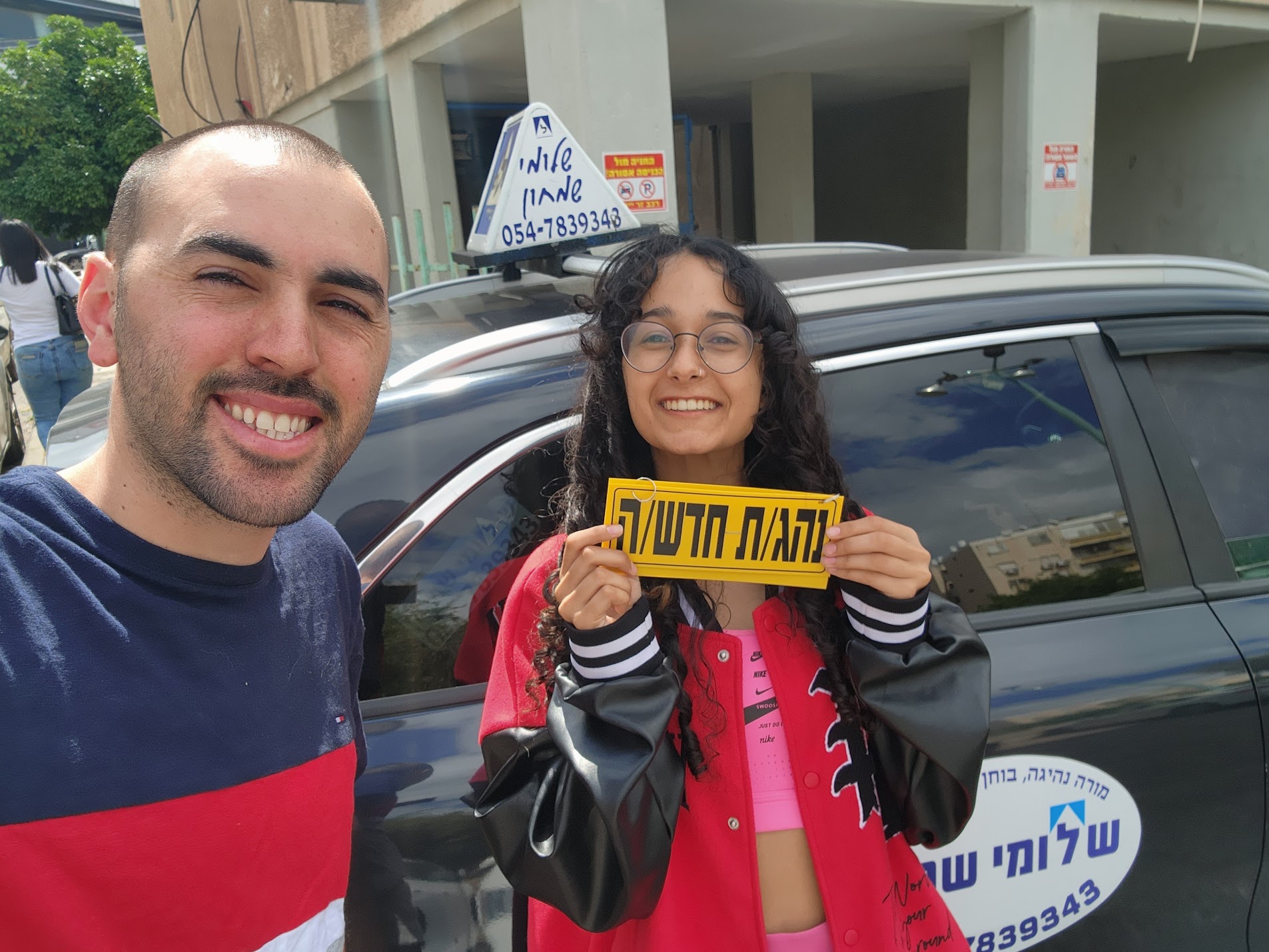 תלמיד עם שלומי שמחון, מורה נהיגה, מחזיק שלט "נהג חדש" לאחר המבחן – תמונה 42