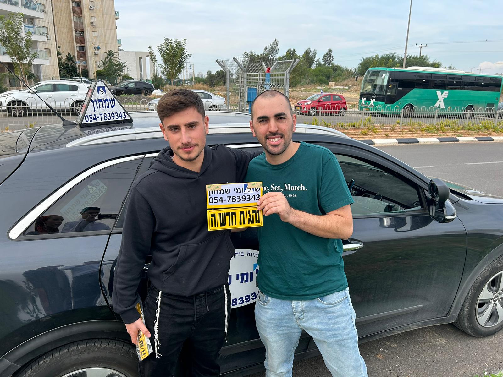 תלמיד עם שלומי שמחון, מורה נהיגה, מחזיק שלט "נהג חדש" לאחר המבחן – תמונה 55