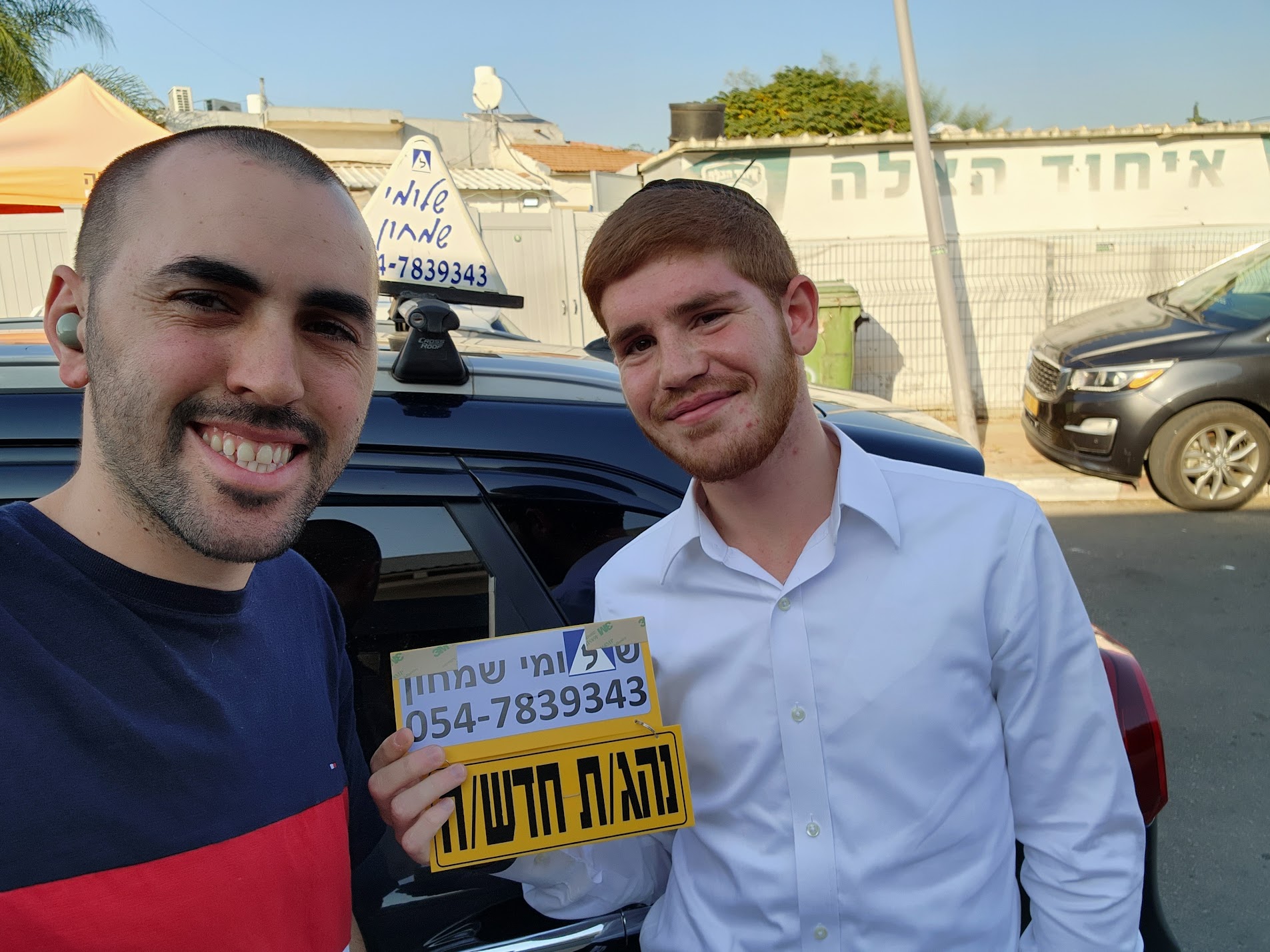 תלמיד עם שלומי שמחון, מורה נהיגה, מחזיק שלט "נהג חדש" לאחר המבחן – תמונה 35