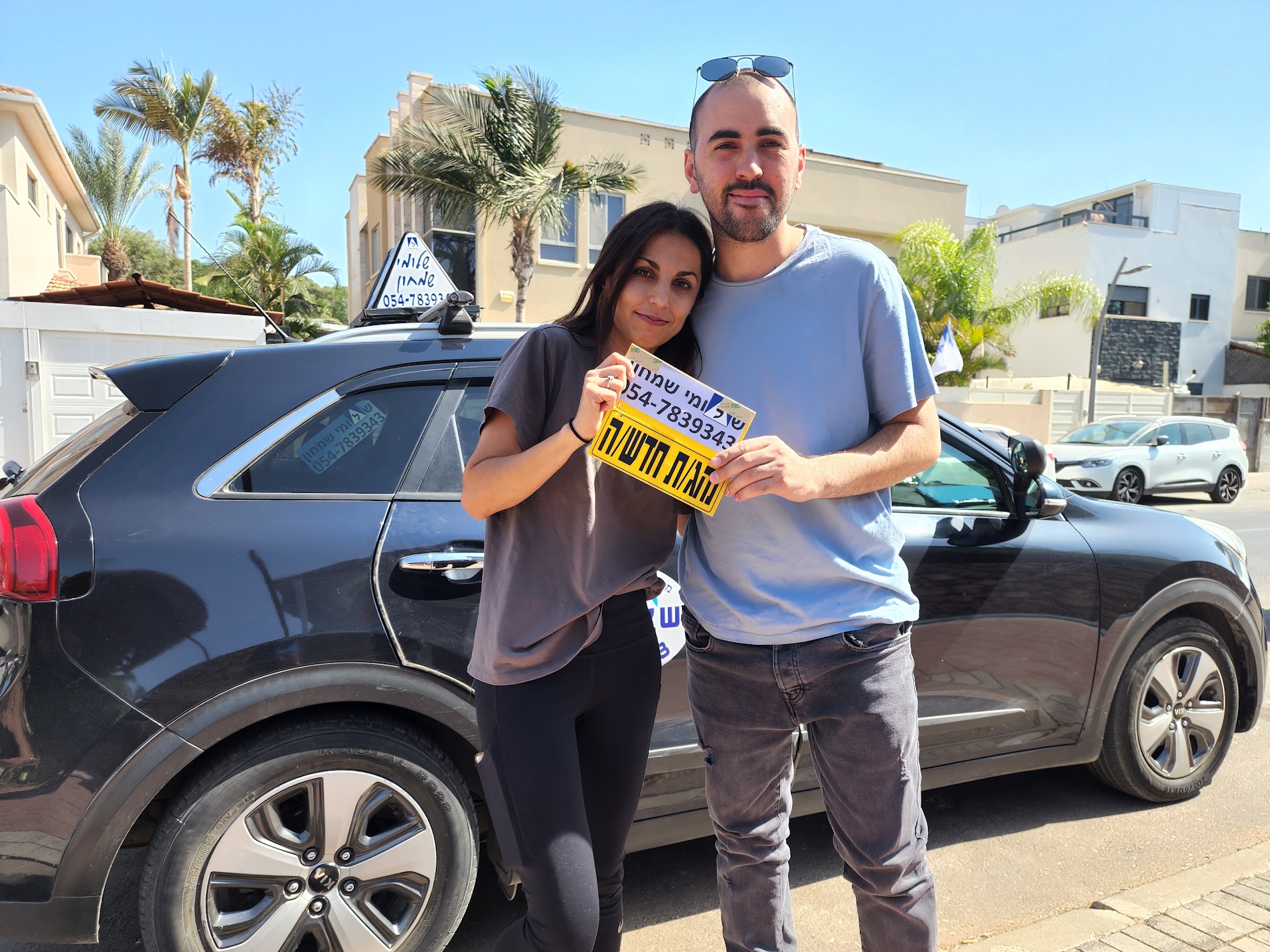 תלמיד עם שלומי שמחון, מורה נהיגה, מחזיק שלט "נהג חדש" לאחר המבחן – תמונה 24